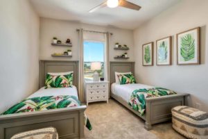 Two twin beds with tropical-design throw pillows, covers, and wall decorations in a stylish bedroom of an Eagle Trace resort residence.
