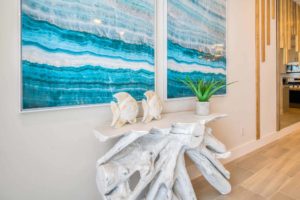 Modern wall art and decorative side table with sculptures of tropical fish and a house plant in an Eagle Trace resort residence.
