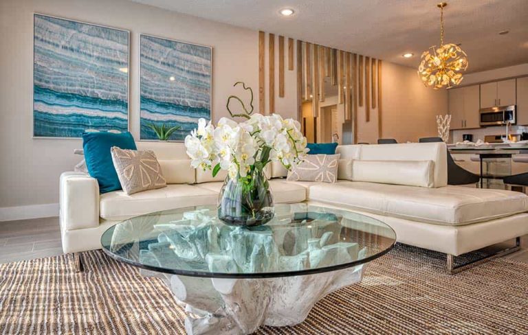 Modern furnished living room with a spacious couch, modern glass coffee table, and a vase of flowers at an Eagle Trace resort residence.